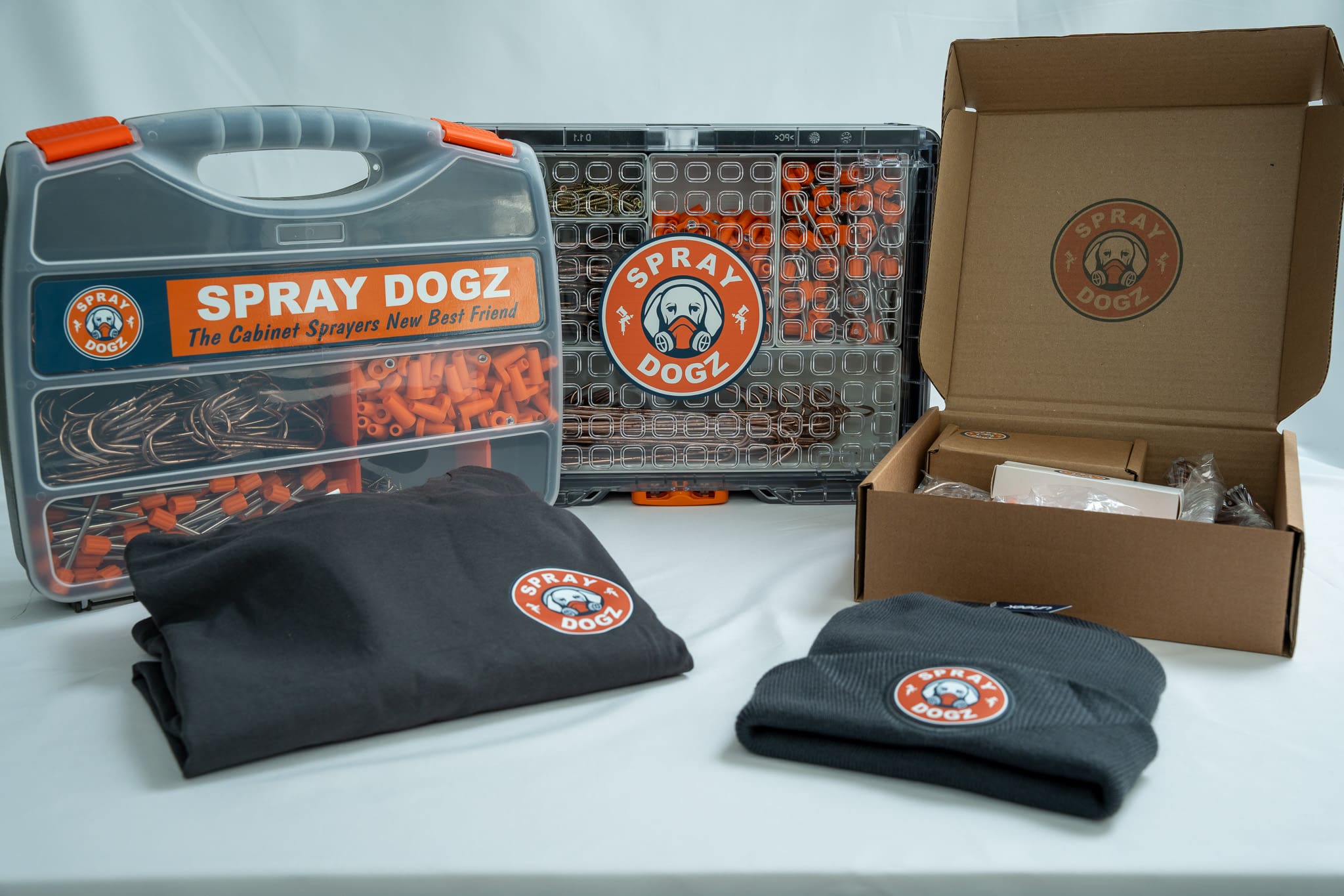 Spray Dogz cabinet door hanging system display featuring product packaging, branded hat, and apparel.